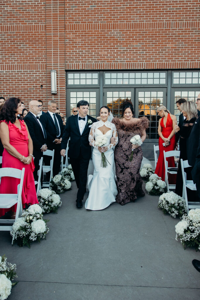 Bride walks down the aisle with parents at new york wedding venue diamond mills