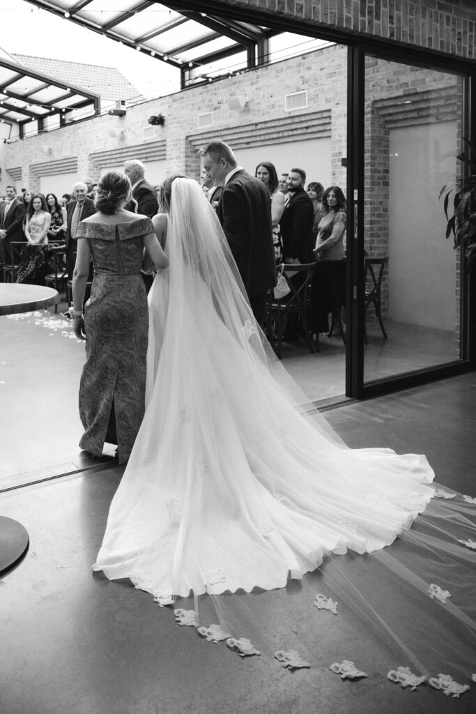 Bride walks down the aisle with parents at Perona Farms NJ