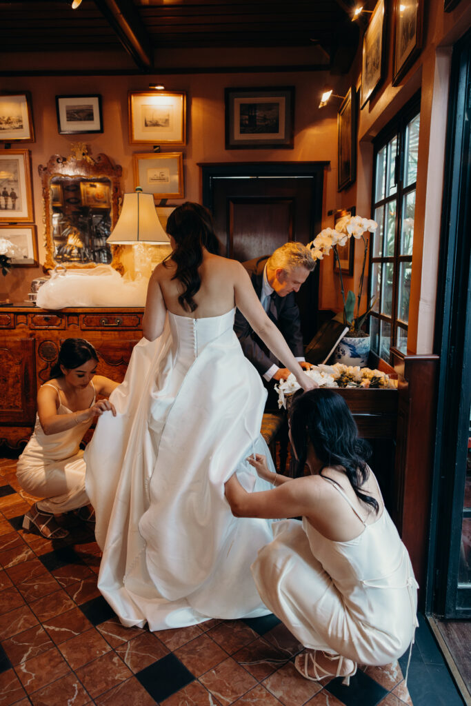 Bridesmaids help bride get ready for cocktail hour at The River Café NYC