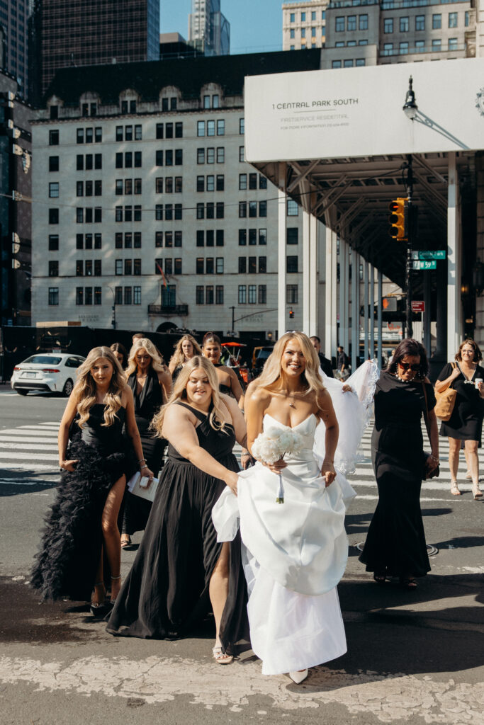 Bridesmaids help bride walk down the road in nyc