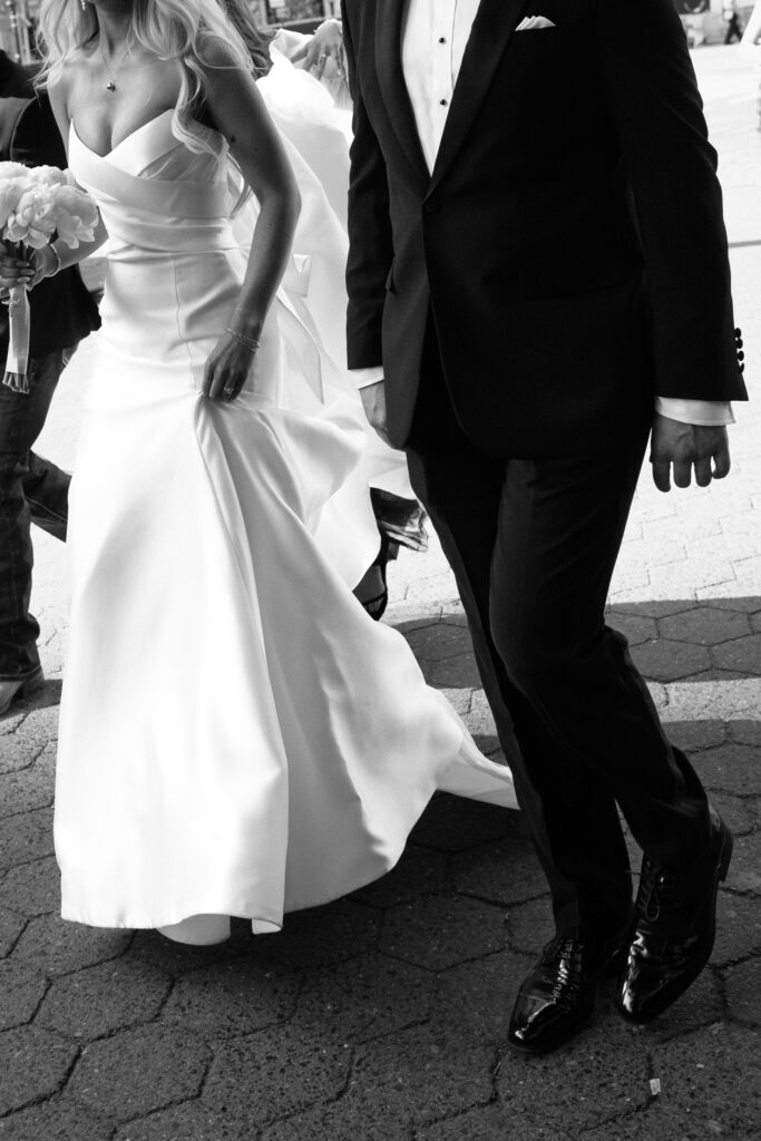Bridesmaids and groomsmen help bride walk down the steps in Central Park