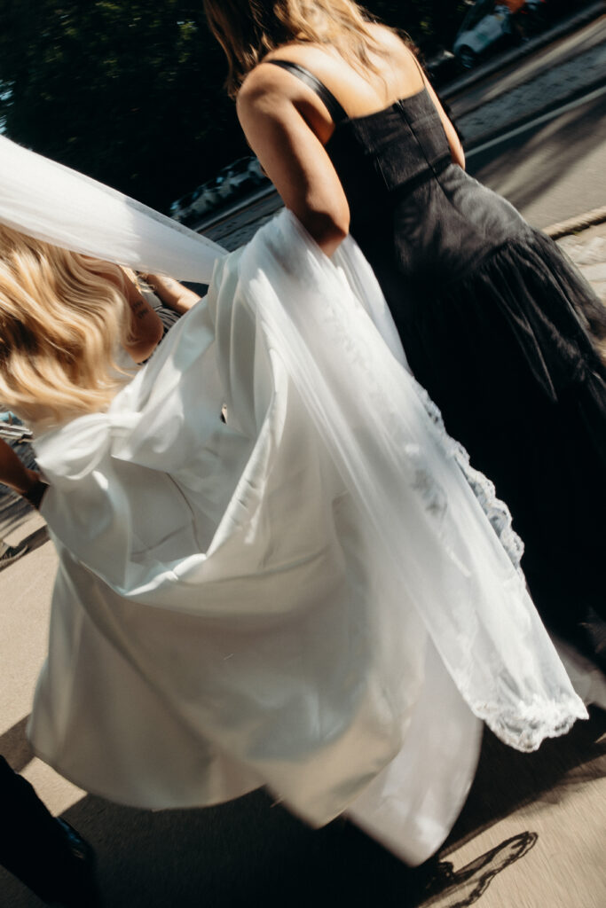 Bridesmaid helps bride walk down the steps in Central Park