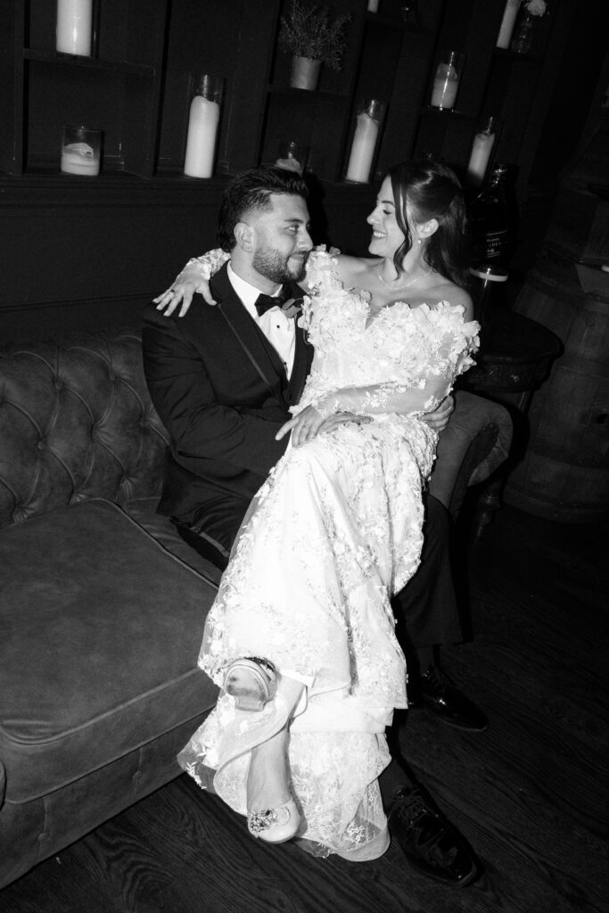 New York bride sitting on groom’s lap at Sea Cliff Manor wedding reception