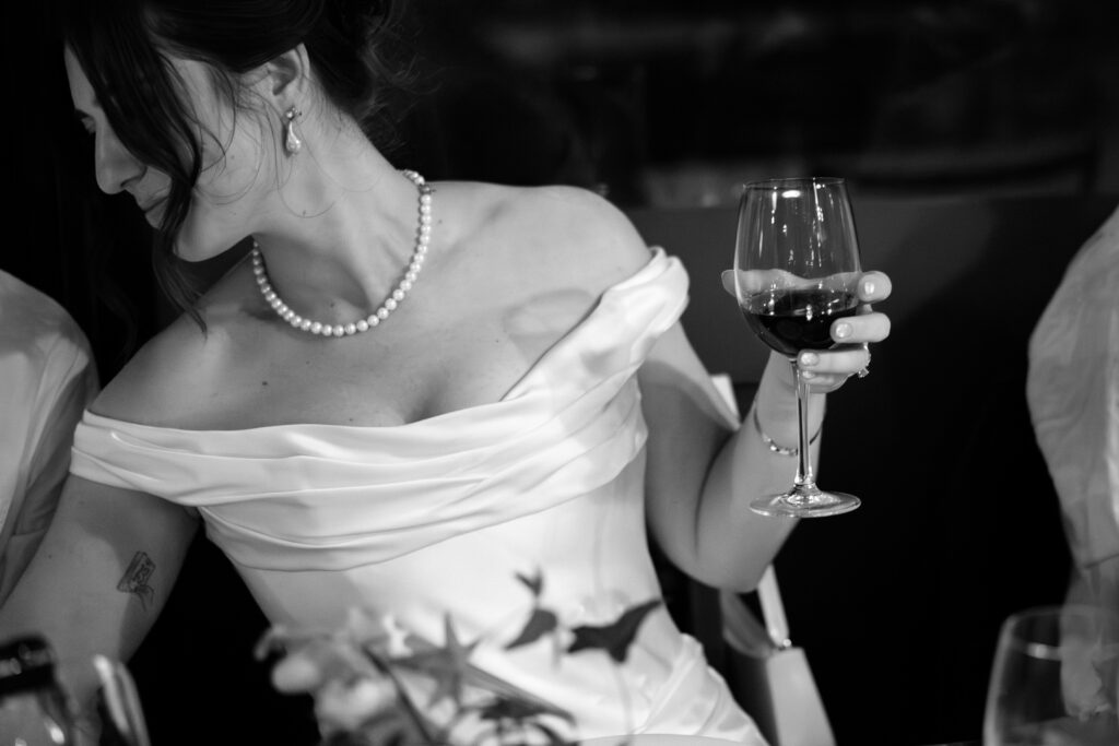 New York bride holding a drink during dinner at her wedding celebration at Aurora Williamsburg