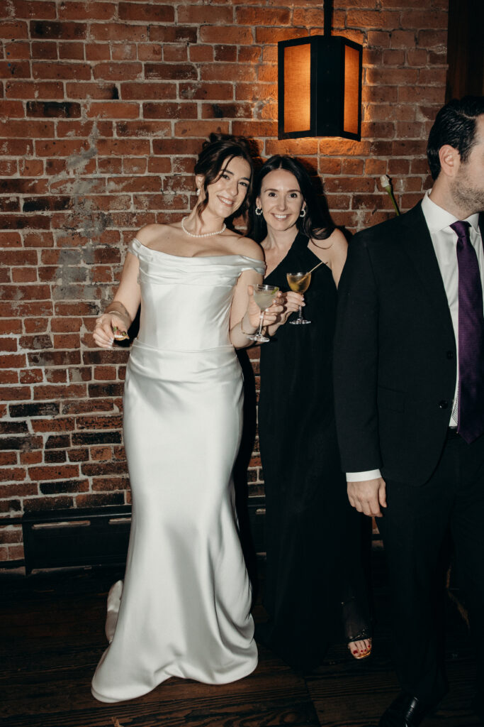 New York bride smiling with a bridesmaid during dinner at her wedding celebration at Aurora Williamsburg