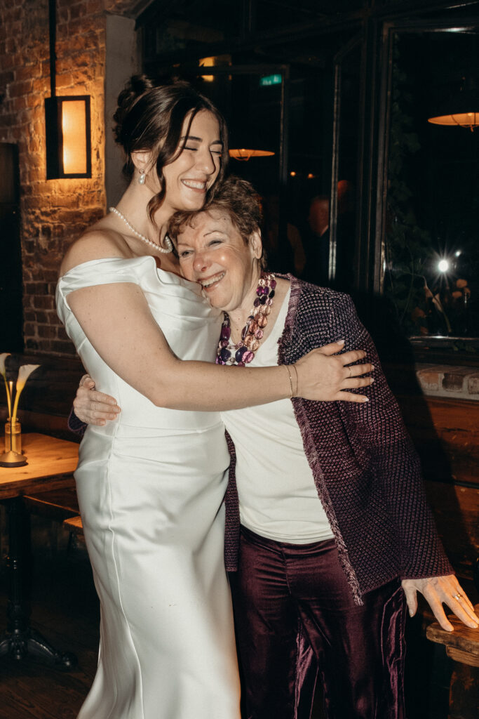 New York bride hugging her grandmother during dinner at her wedding celebration at Aurora Williamsburg