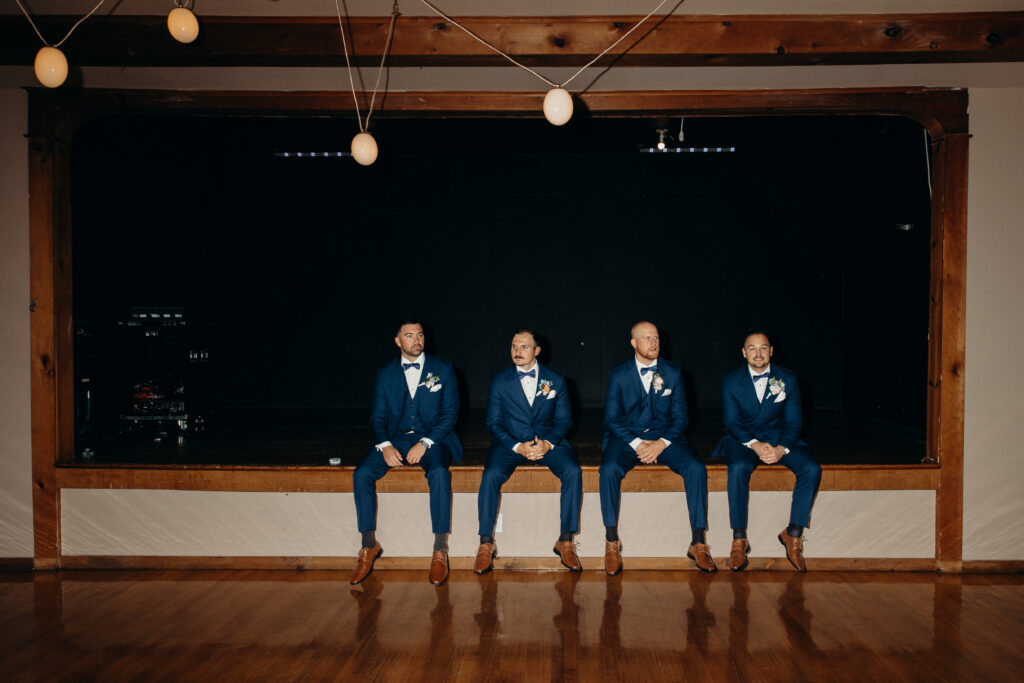 Groomsmen sitting on a stage at Arrow Park New York wedding