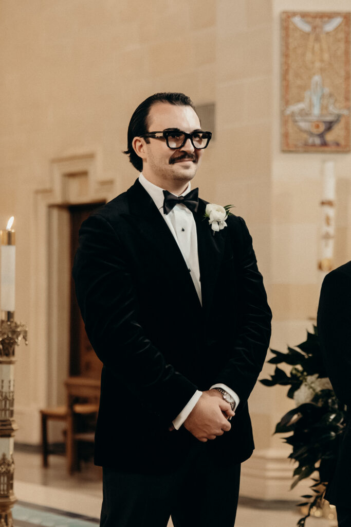 Groom watching the bride walk down the aisle during the wedding ceremony at a New York church wedding