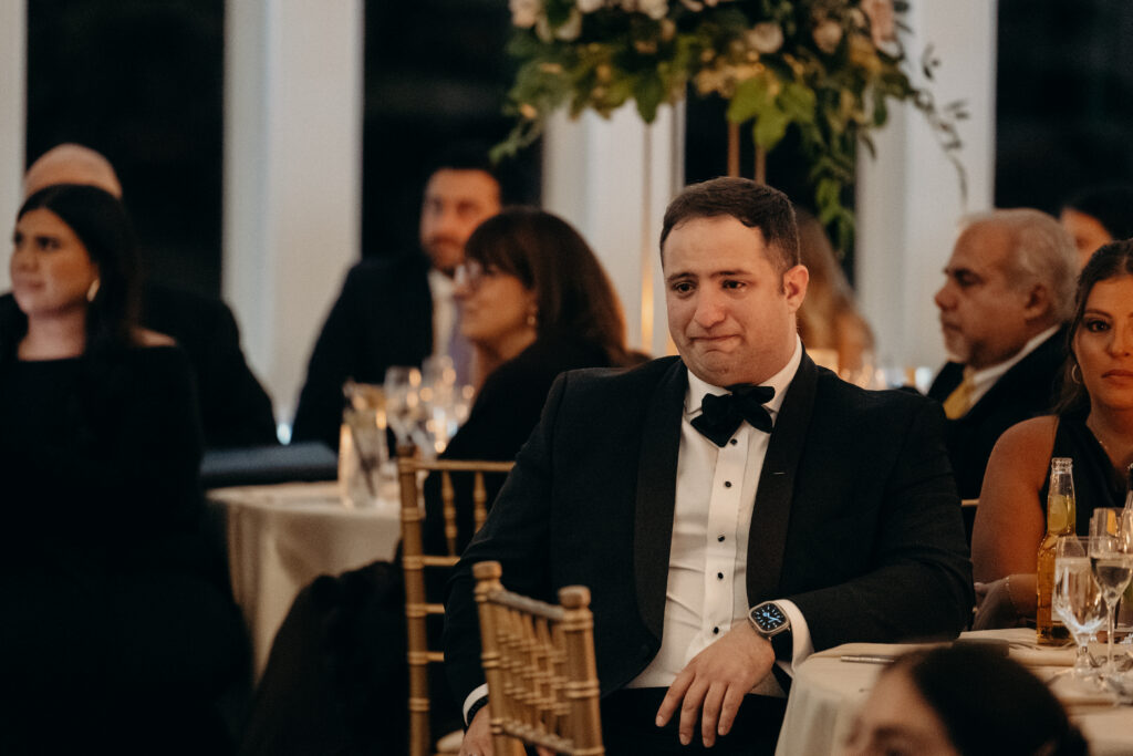 Groomsman watching couple dancing during first dance at Le Chateau New York wedding reception