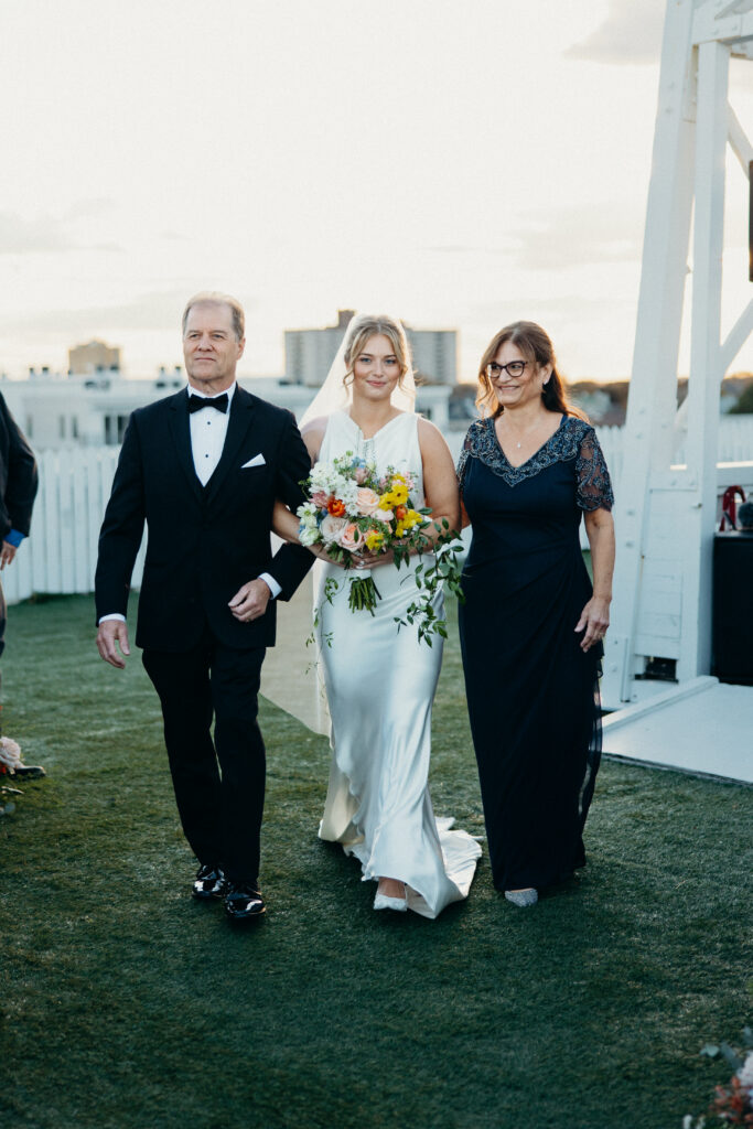 Bride walking down the aisle with her parents at The Asbury Hotel wedding ceremony