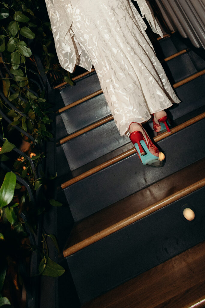 Bride walking down stairs in red heels at Madeline’s wedding