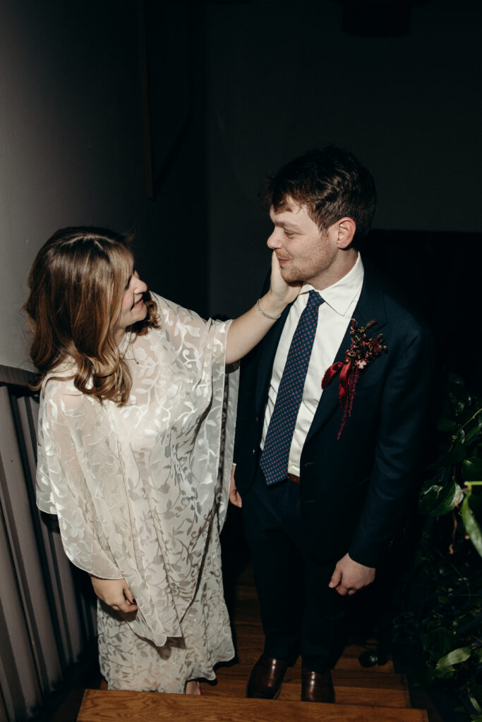 Bride touching groom’s face during wedding reception moment