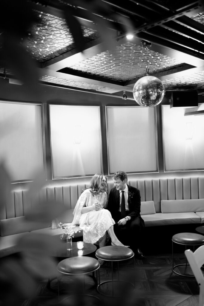 Black and white candid of couple under disco ball at reception