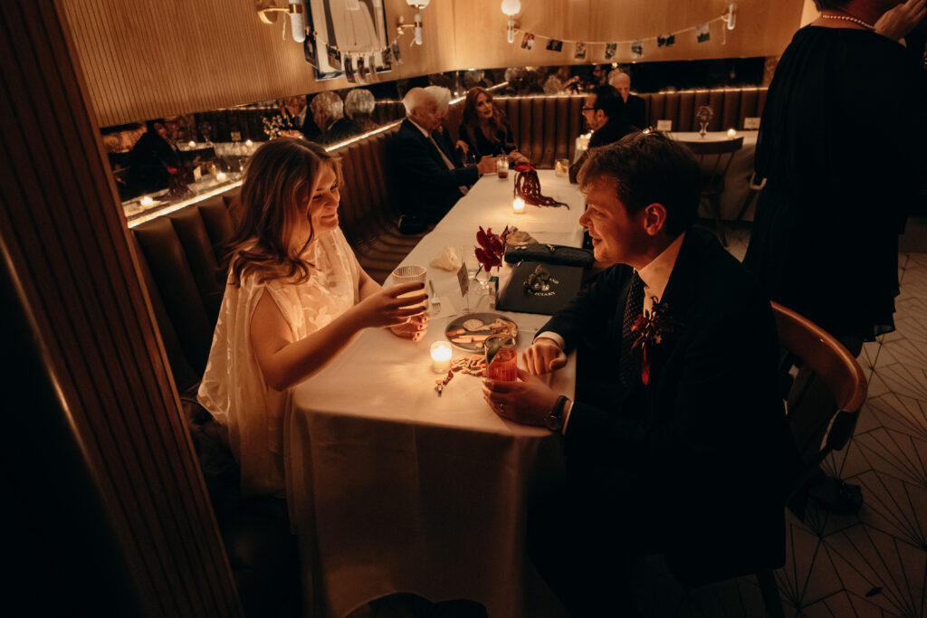 Bride and groom sharing drinks at intimate candlelit reception table in Brooklyn