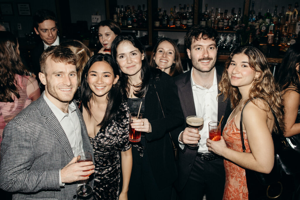 Group of guests smiling and posing at the bar during reception