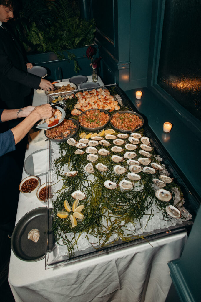 Guests serving oysters and shrimp from a seafood display at wedding reception in Brooklyn