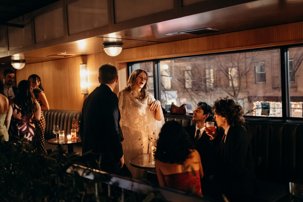 Bride laughing with guests while holding drinks during reception celebration