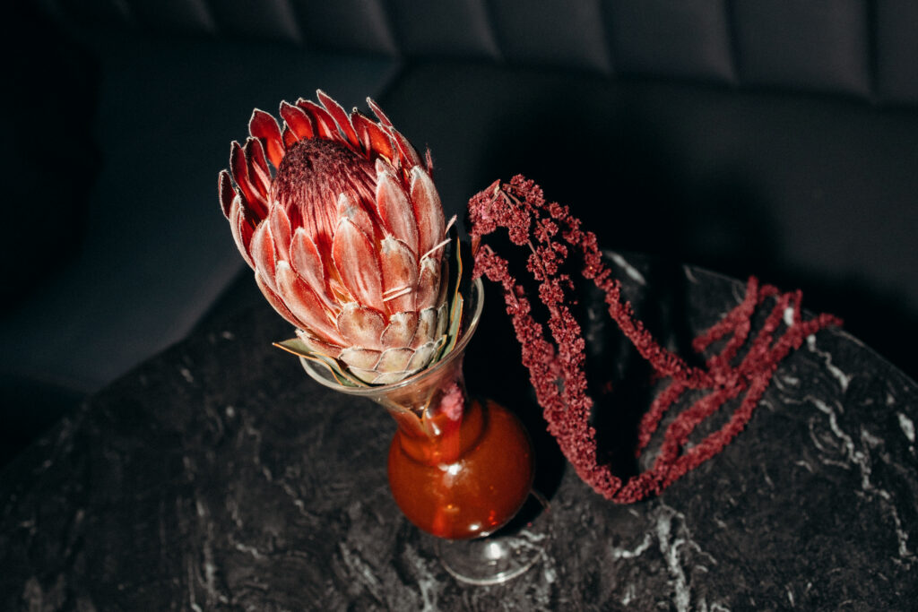 Floral arrangement with red protea centerpiece at wedding reception table
