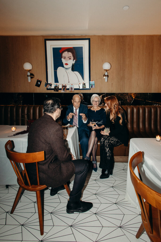 Wedding guests chatting at candlelit table with framed artwork at Madeline’s Brooklyn