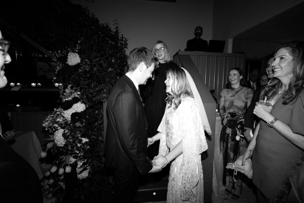 Black and white photo of couple holding hands during wedding ceremony