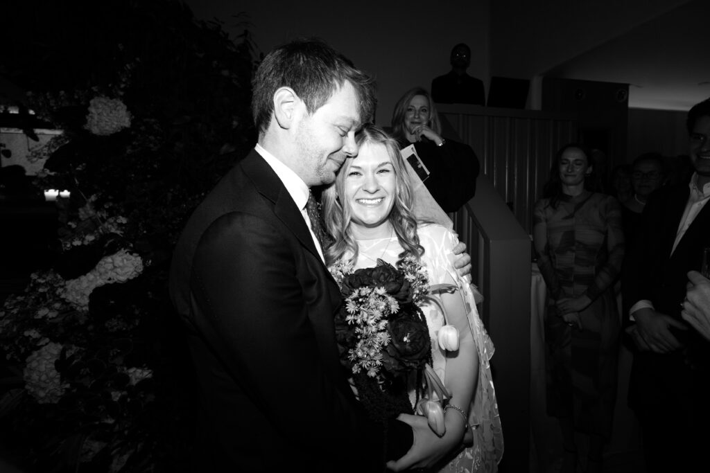 Bride and groom embracing with bouquet after ceremony