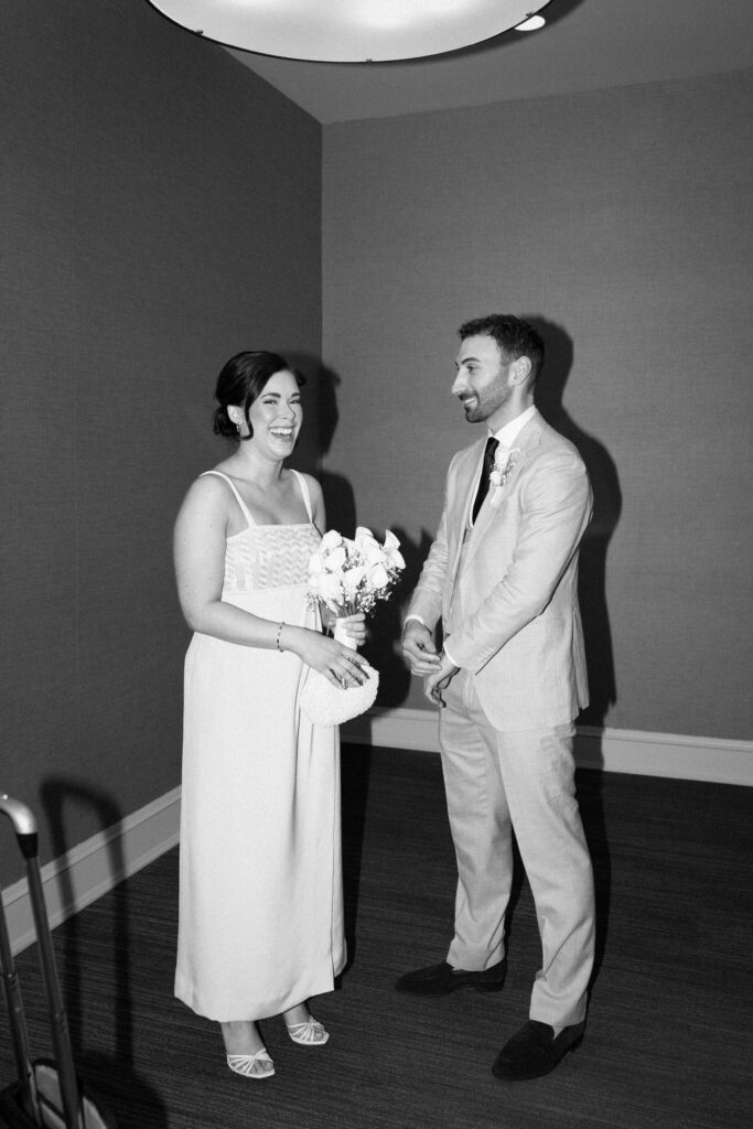 Bride and groom laughing together indoors during their intimate wedding celebration