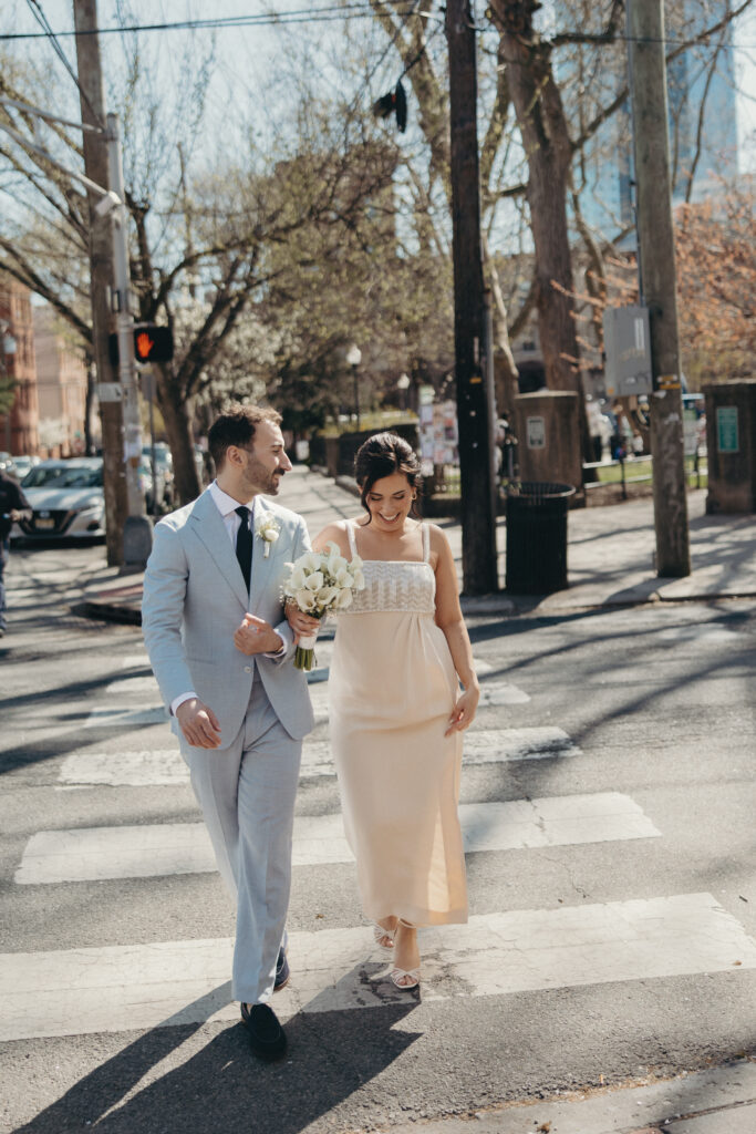 Bride and groom walking across a city crosswalk together on their wedding day
