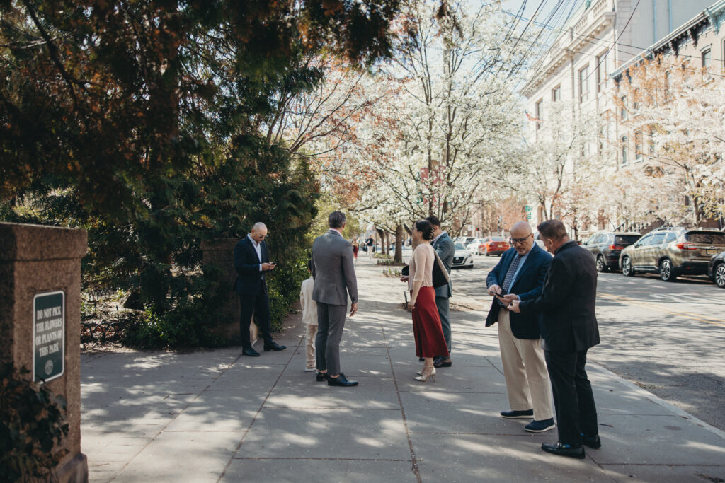 Wedding guests arriving at a Jersey City park ceremony on a sunny spring afternoon