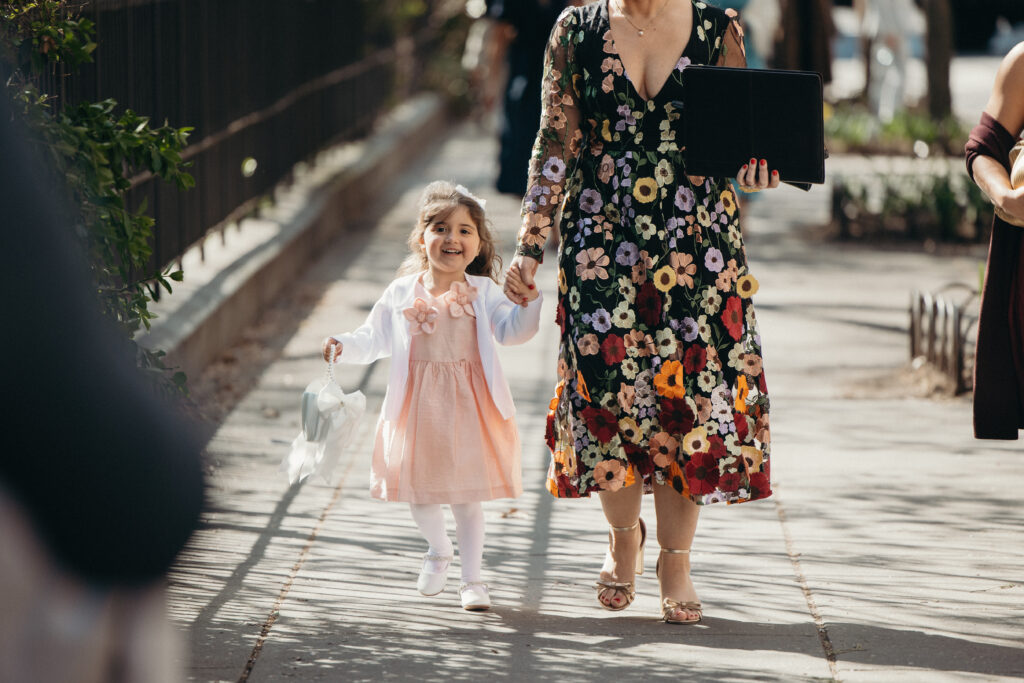 Flower girl walking hand in hand with a guest before the outdoor wedding ceremony in Jersey City