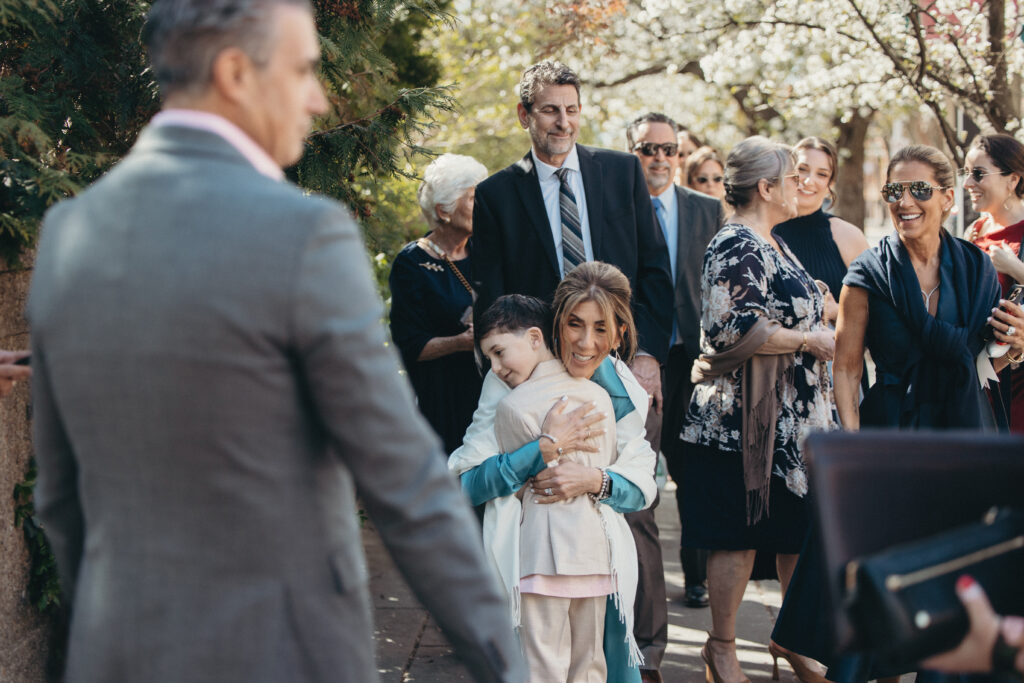 Family members hugging and greeting one another before the spring wedding ceremony outdoors