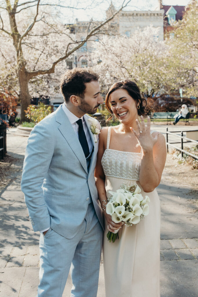 Bride showing off her wedding ring while smiling beside the groom after their ceremony