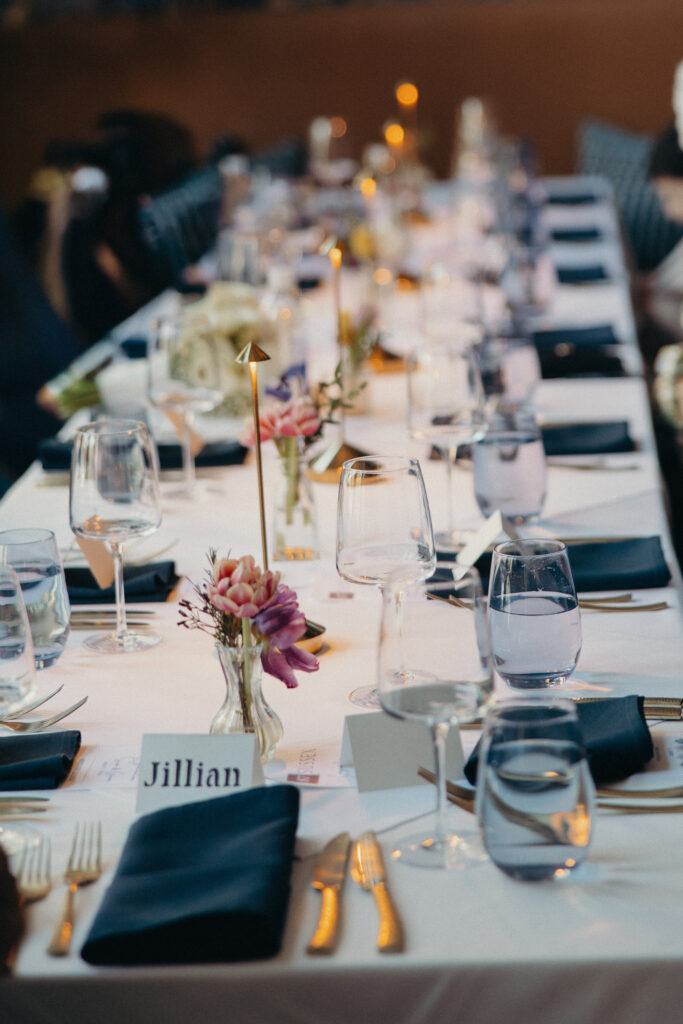 Reception table details with floral bud vases, candles, black napkins, and elegant place settings