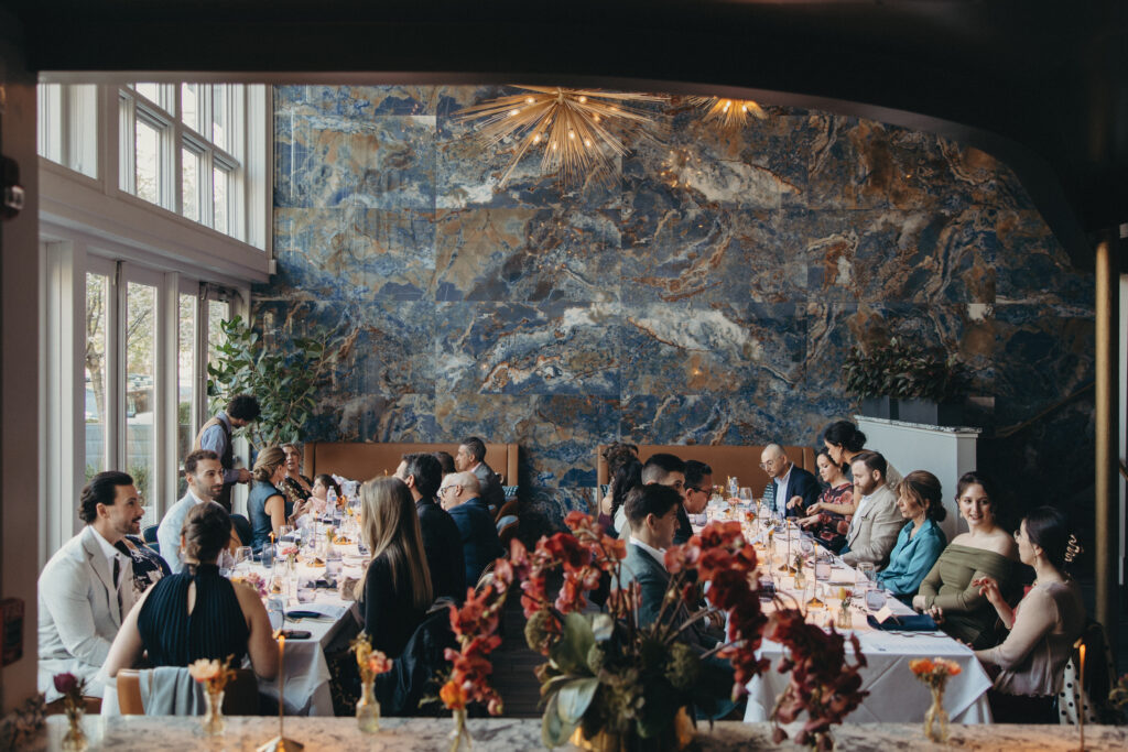 Intimate wedding dinner reception at 87 Sussex with guests gathered beneath modern chandeliers and marble walls