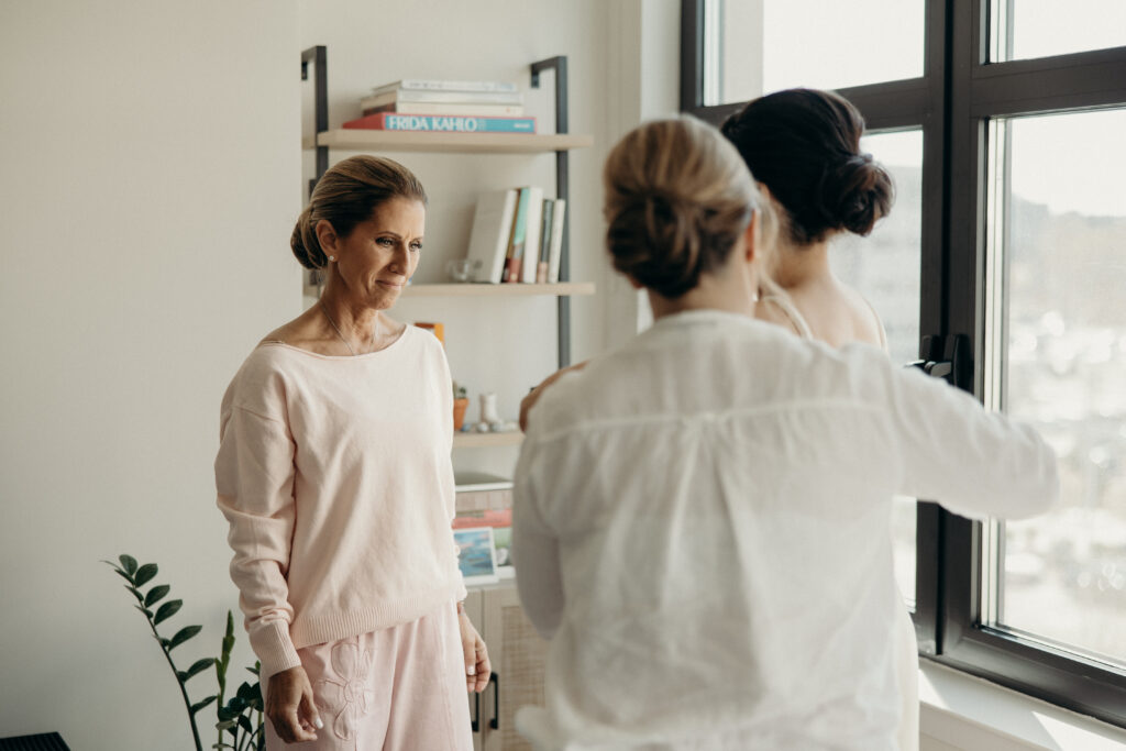 Emotional getting-ready moment between the bride, her mother, and another family member near the window