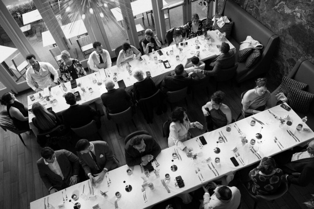 Overhead black and white view of guests seated together during the intimate wedding reception dinner