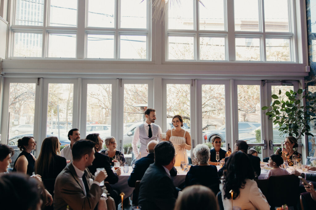 Sean and Giana giving a heartfelt wedding toast surrounded by family and friends during the reception