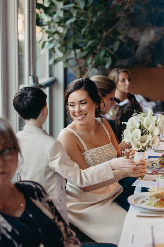 Bride smiling while speaking with a young guest during the intimate wedding reception dinner