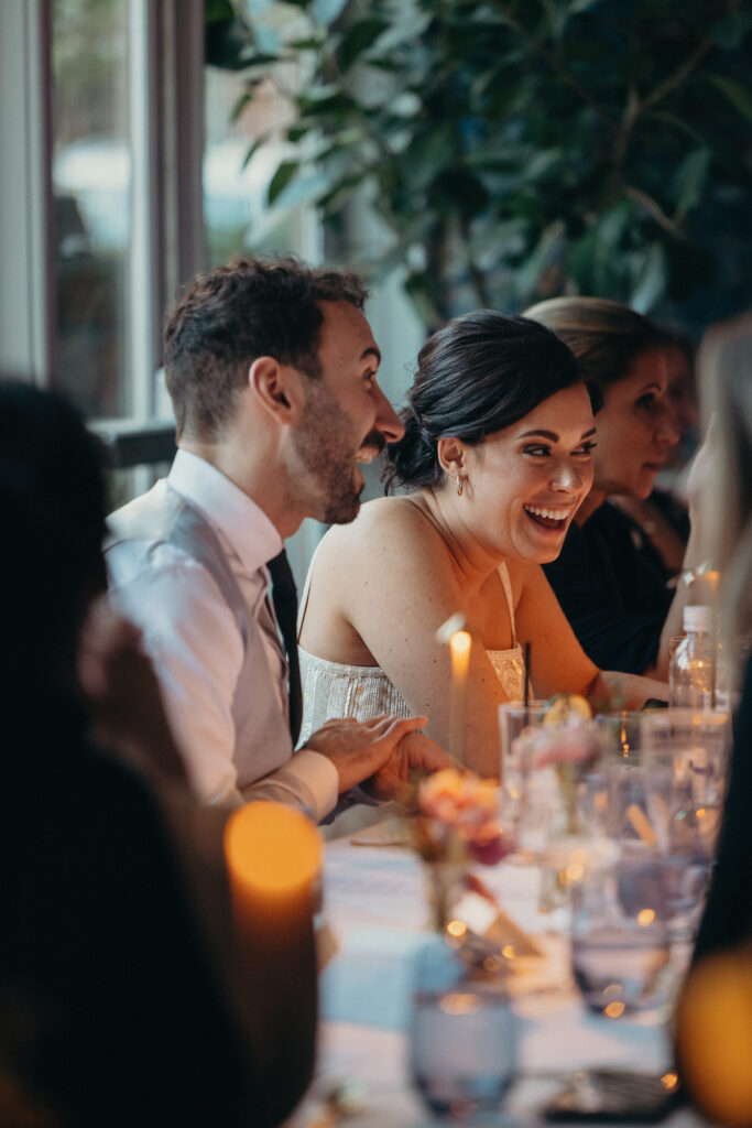 Bride and groom laughing together during speeches at their intimate restaurant wedding reception