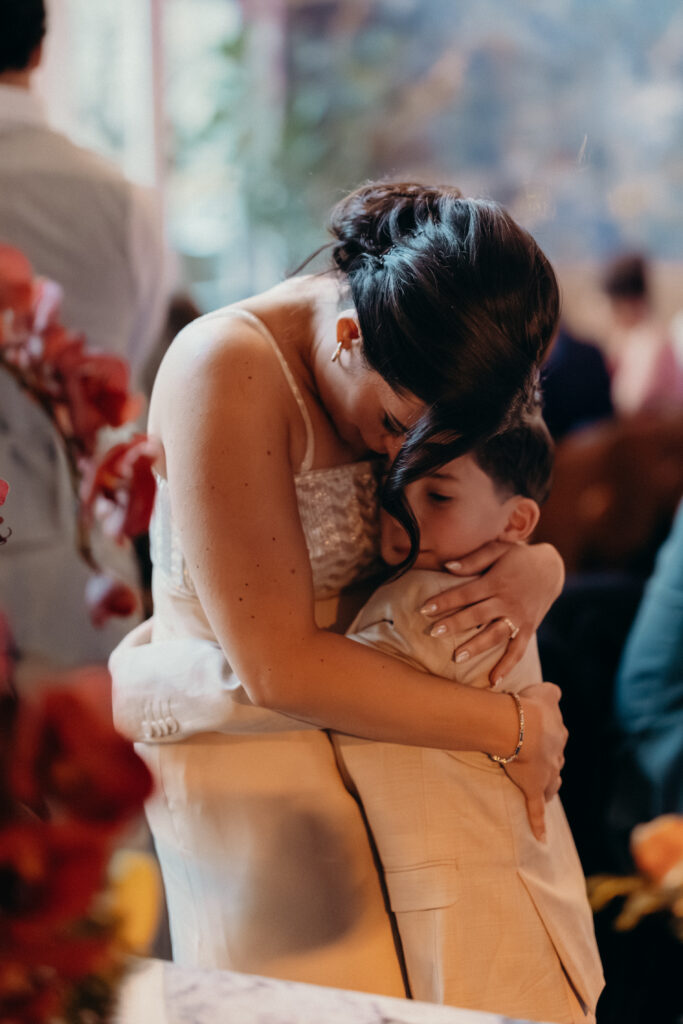 Emotional candid of the bride hugging a young guest during the wedding reception celebration