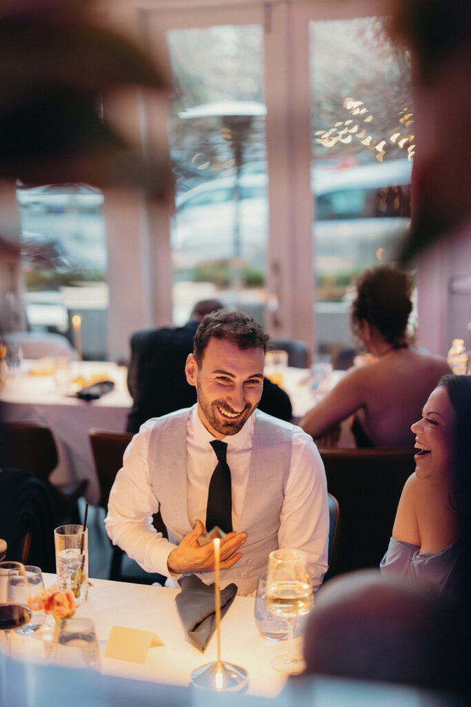 Groom smiling across the dinner table during the candlelit wedding reception at 87 Sussex
