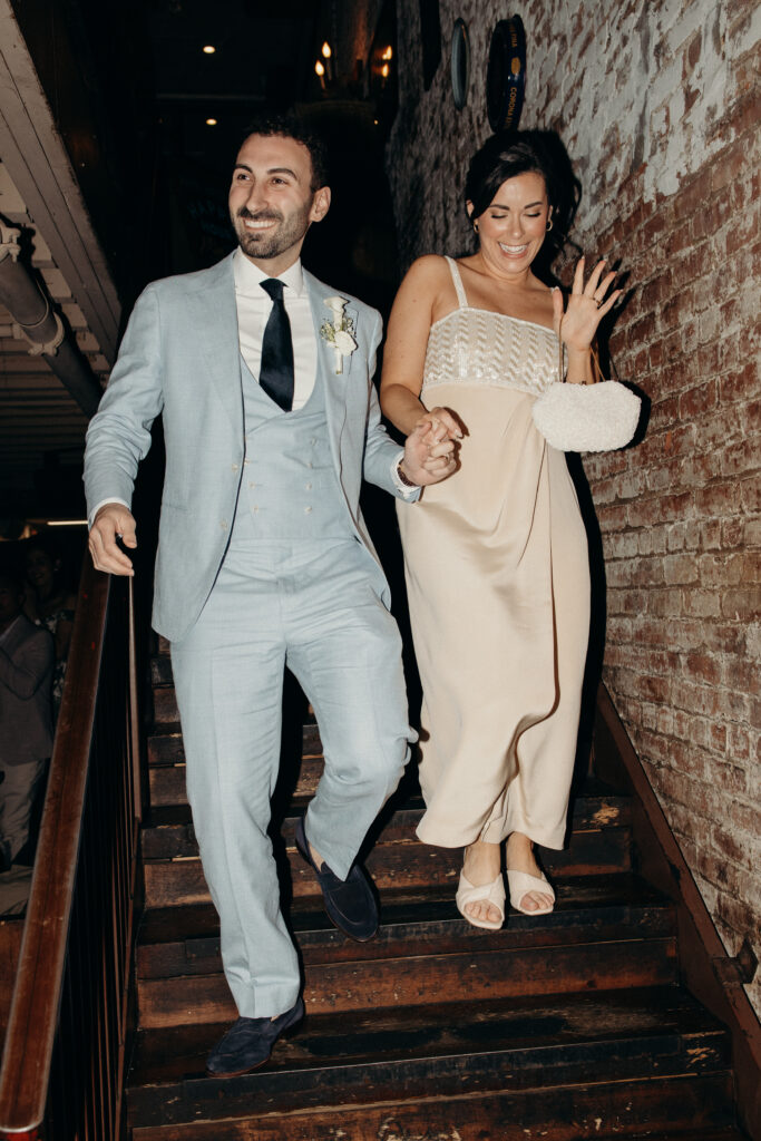 Sean and Giana walking down a staircase hand in hand during their Jersey City elopement celebration