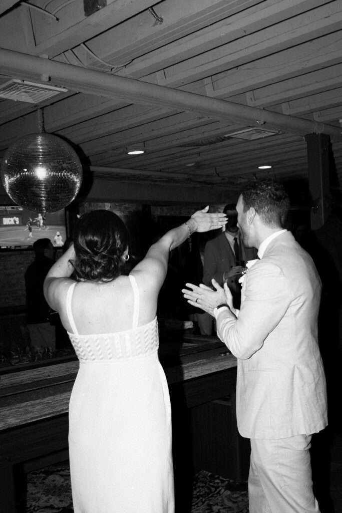 Sean and Giana clapping and dancing together under a disco ball during their Jersey City elopement celebration