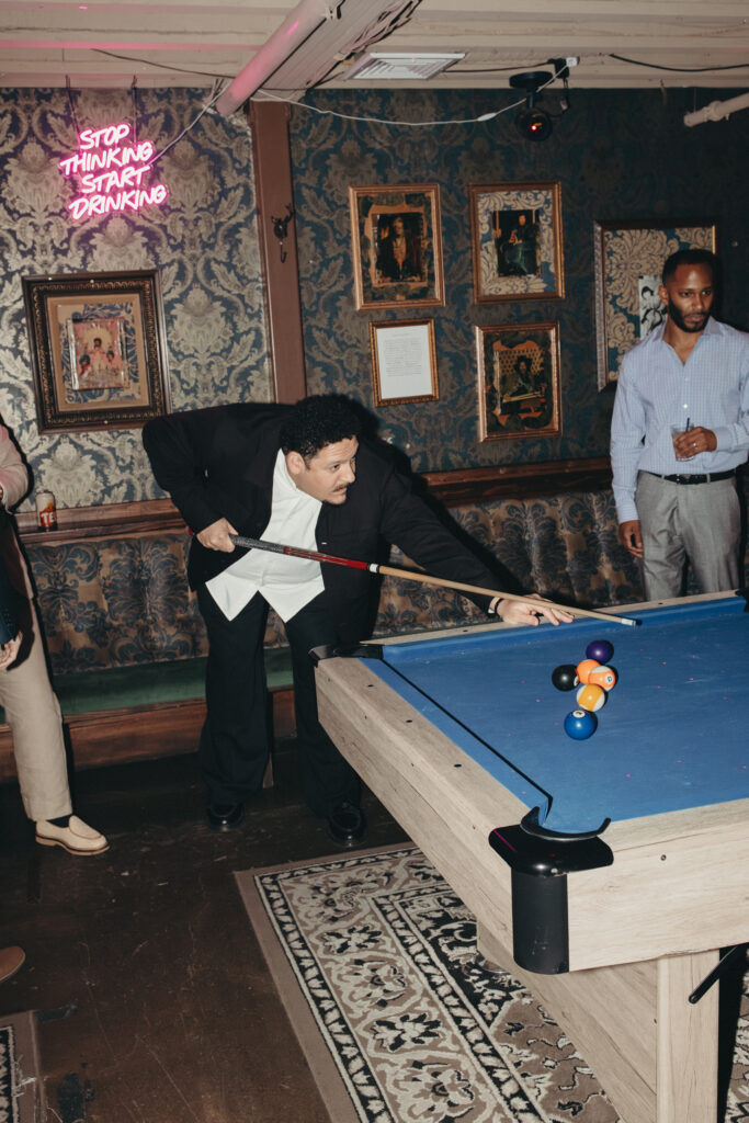 Wedding guest playing pool beneath a neon sign during Sean and Giana’s Jersey City elopement reception