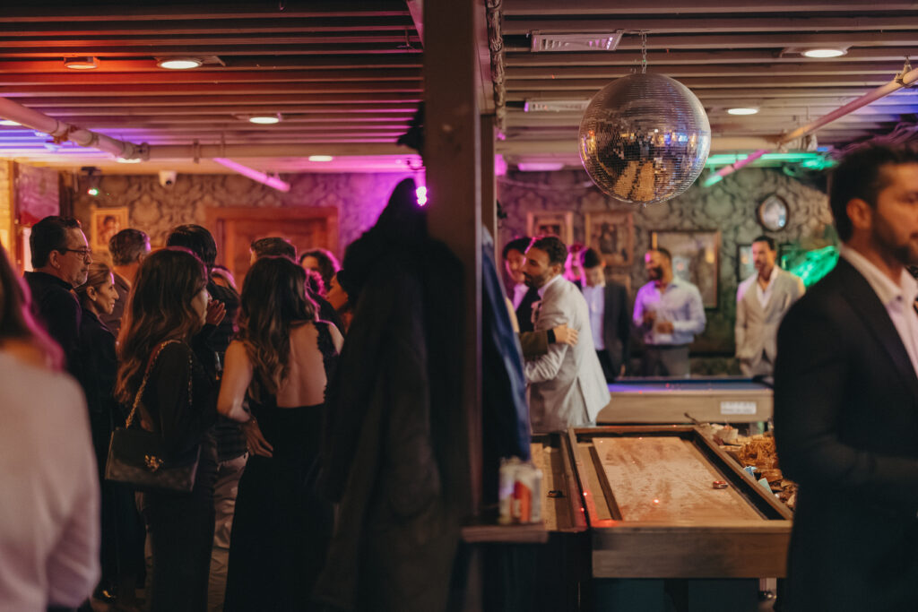 Guests mingling and celebrating inside the dimly lit reception venue during Sean and Giana’s Jersey City elopement