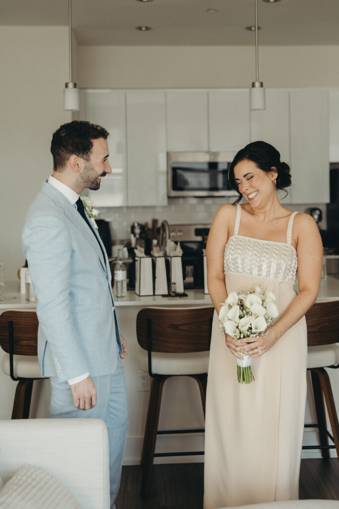 Bride and groom smiling at each other indoors before their intimate wedding ceremony