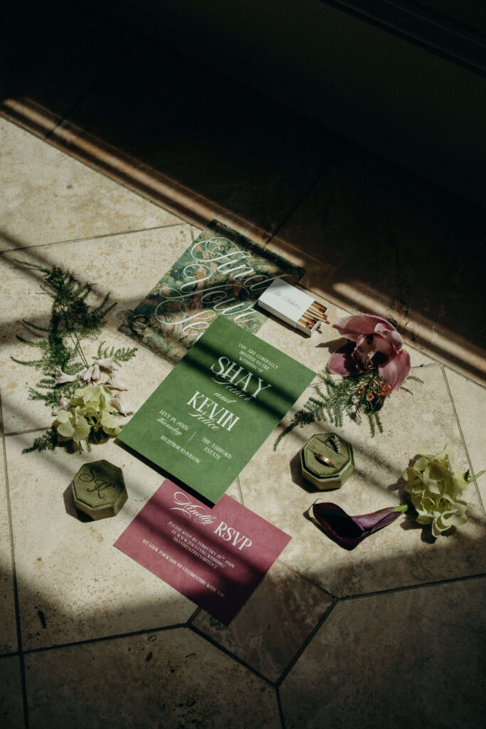 Flat lay of Shay and Kevin's wedding invitations, florals, rings, and stationery at The Ashford Estate