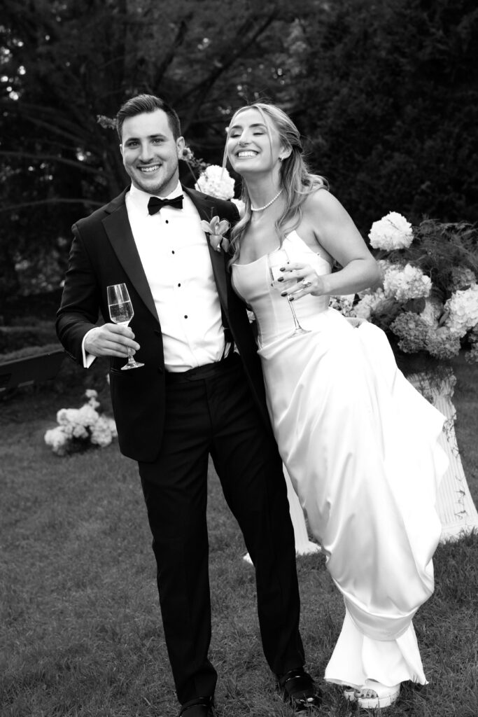 Black and white portrait of Shay and Kevin celebrating with champagne after the ceremony