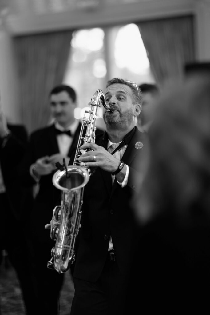 Black and white photo of a musician playing the saxophone for guests at The Ashford Estate