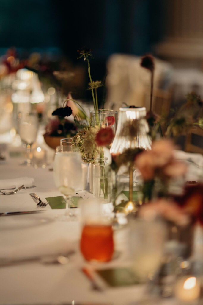 Close-up, soft-focus shot of elegant floral centrepieces and glassware on a reception table at The Ashford Estate