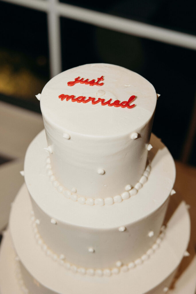 Close-up of a white wedding cake with red "just married" script icing at The Ashford Estate
